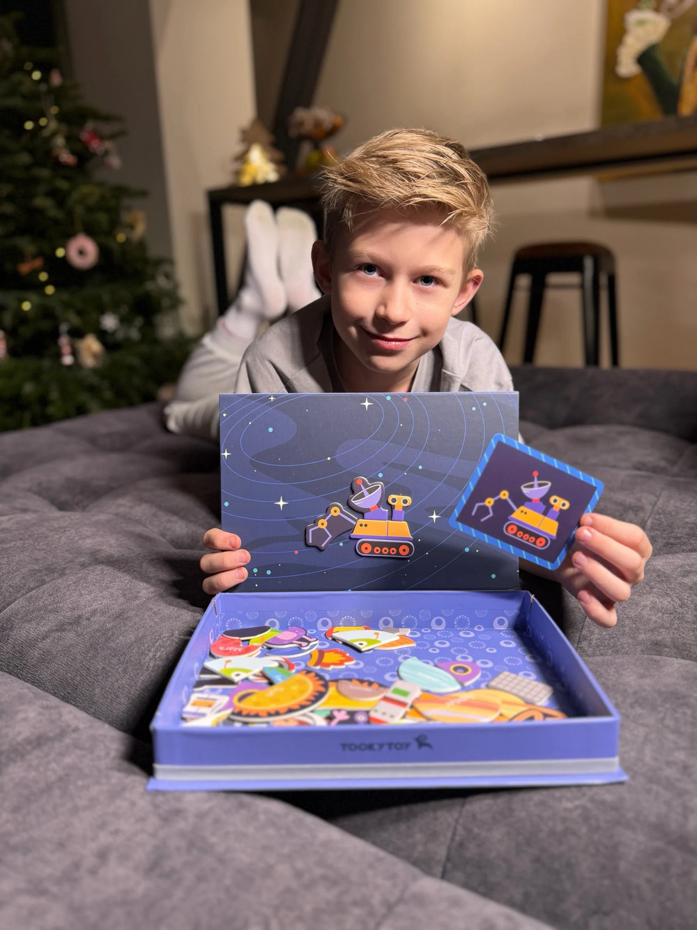 A male kid confidently looking at the camera while holding Tix&Mix space exploration toy set.