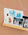 A Tix&Mix Treasure Shelf with photos on a brown wall with colorful scribbles.