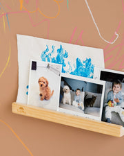 A Tix&Mix Treasure Shelf with photos on a brown wall with colorful scribbles.