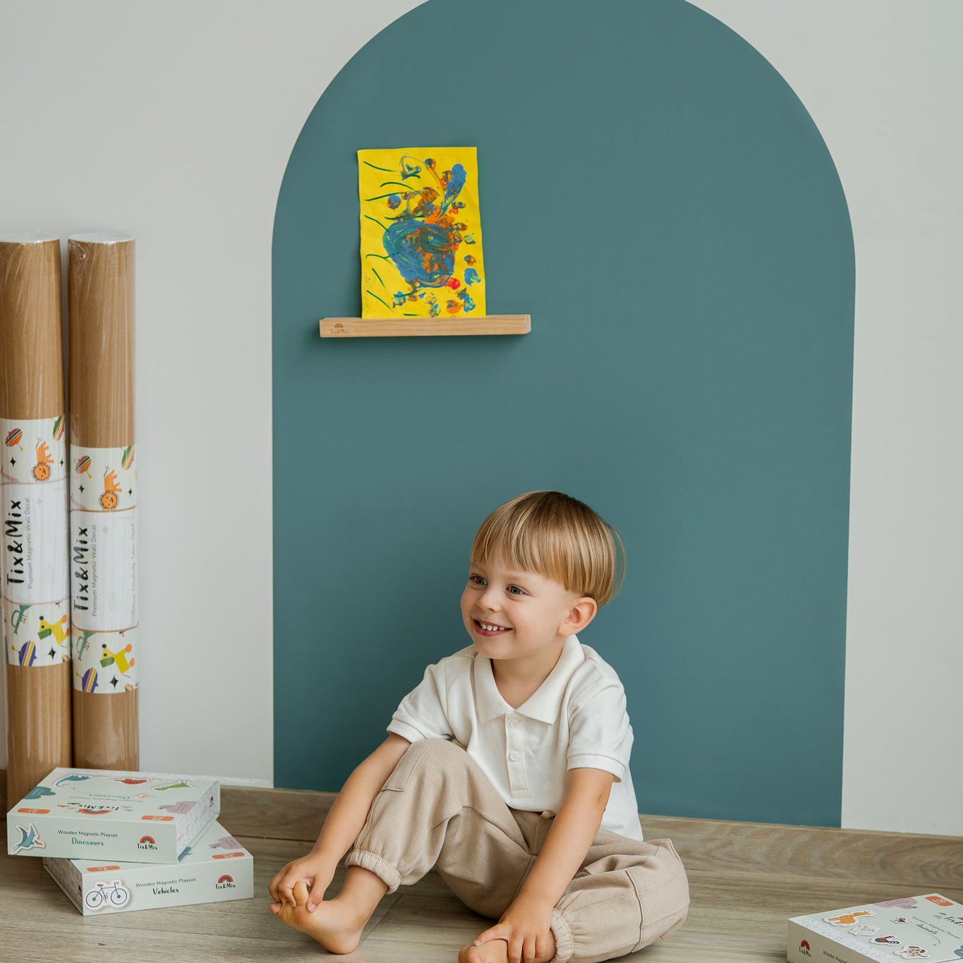 A child sitting happily infront of Tix&Mix blue magnetic wall decal.