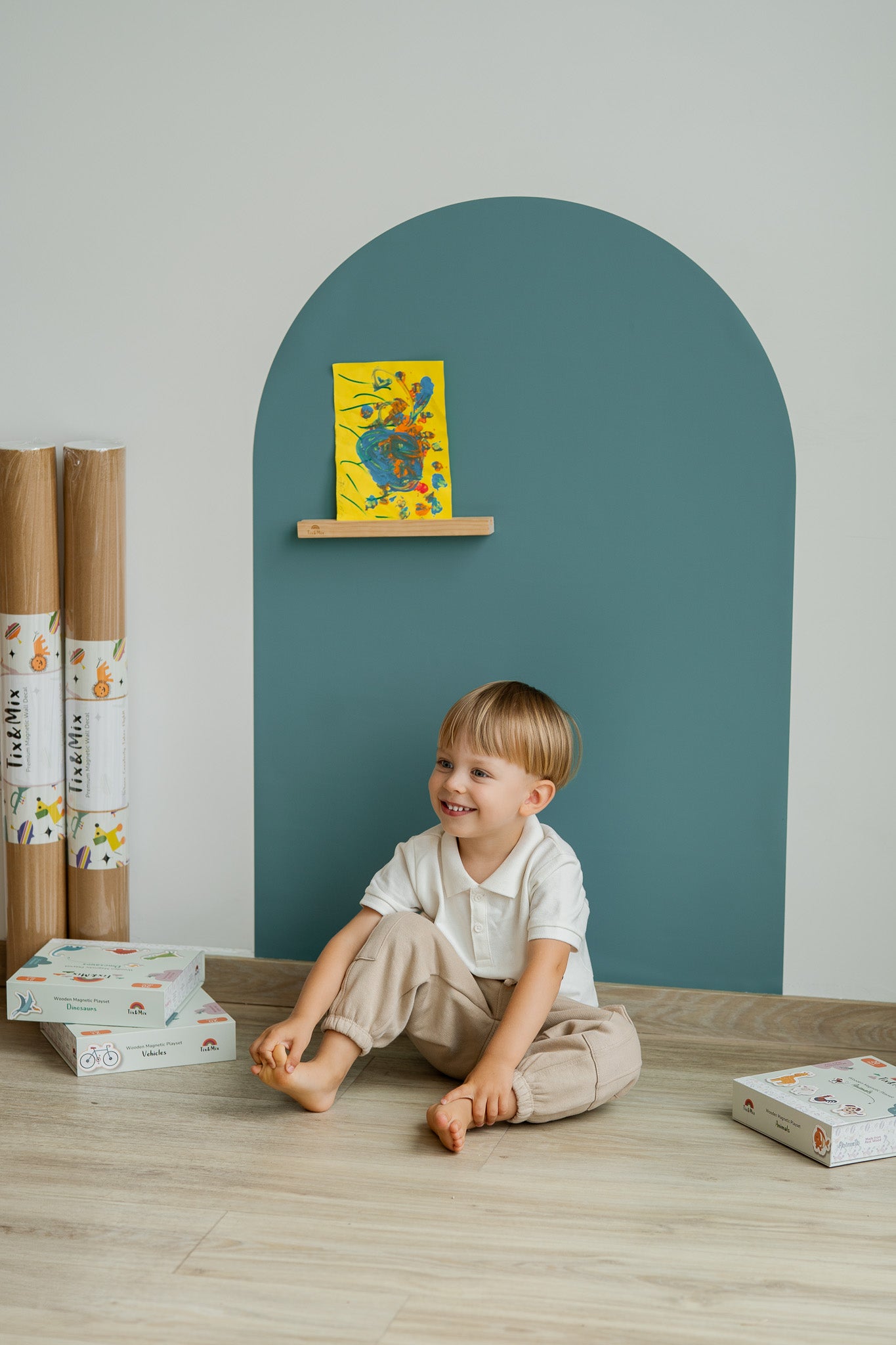 A child sitting happily infront of Tix&Mix blue magnetic wall decal.