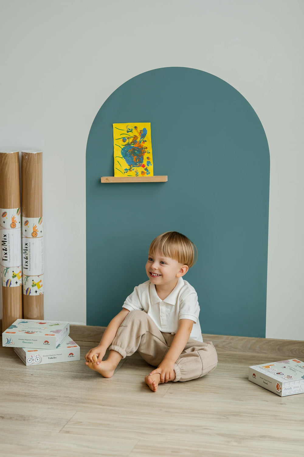 A toddler smiling while sitting in front of Tix&Mix cyan wave magnetic wall decal.