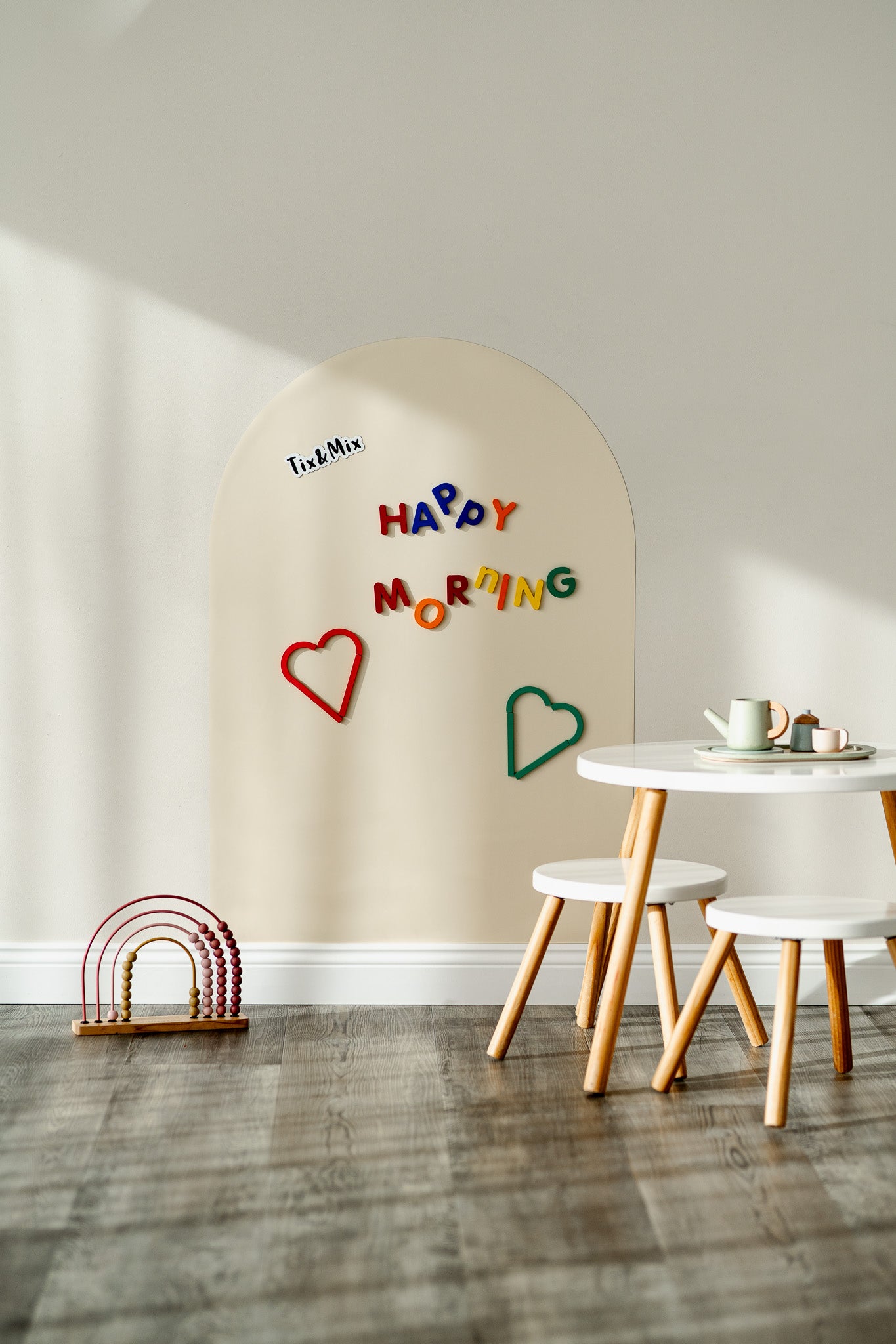 A white magnetic wall decal on a clean white wall with Tix&Mix magnetic letters placed on it.