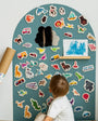 A toddler looking at the Tix&Mix magnetic wooden toys and accessories placed on a cyan wave magnetic wall decal.