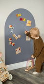 A toddler solving animals puzzle on a Tix&Mix grey magnetic wall decal.