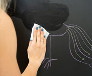 A girl erasing the drawing on a black magnetic wall decal.