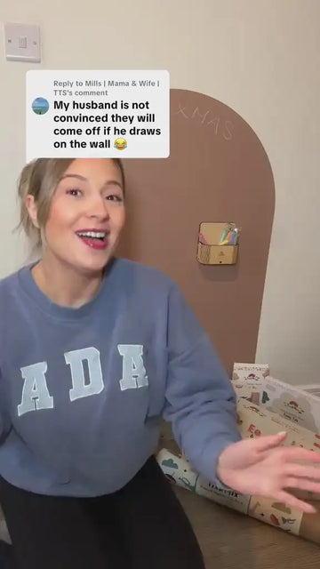A woman showcasing that crayons can be erased from the magnetic wall decal using wet wipes.