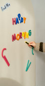 A hand placing rings and blocks set on a white magnetic wall decal.
