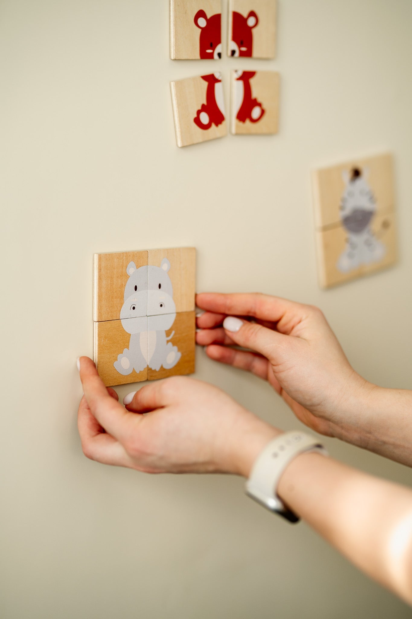 A hand arranging an animal puzzle on a Tix&Mix magnetic wall decal.