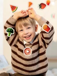 A happy male toddler looking at the camera while featuring Tix&Mix magnetic food toys.