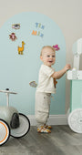 A toddler standing happily in front of Tix&Mix magnetic wall decal in blue dream color.