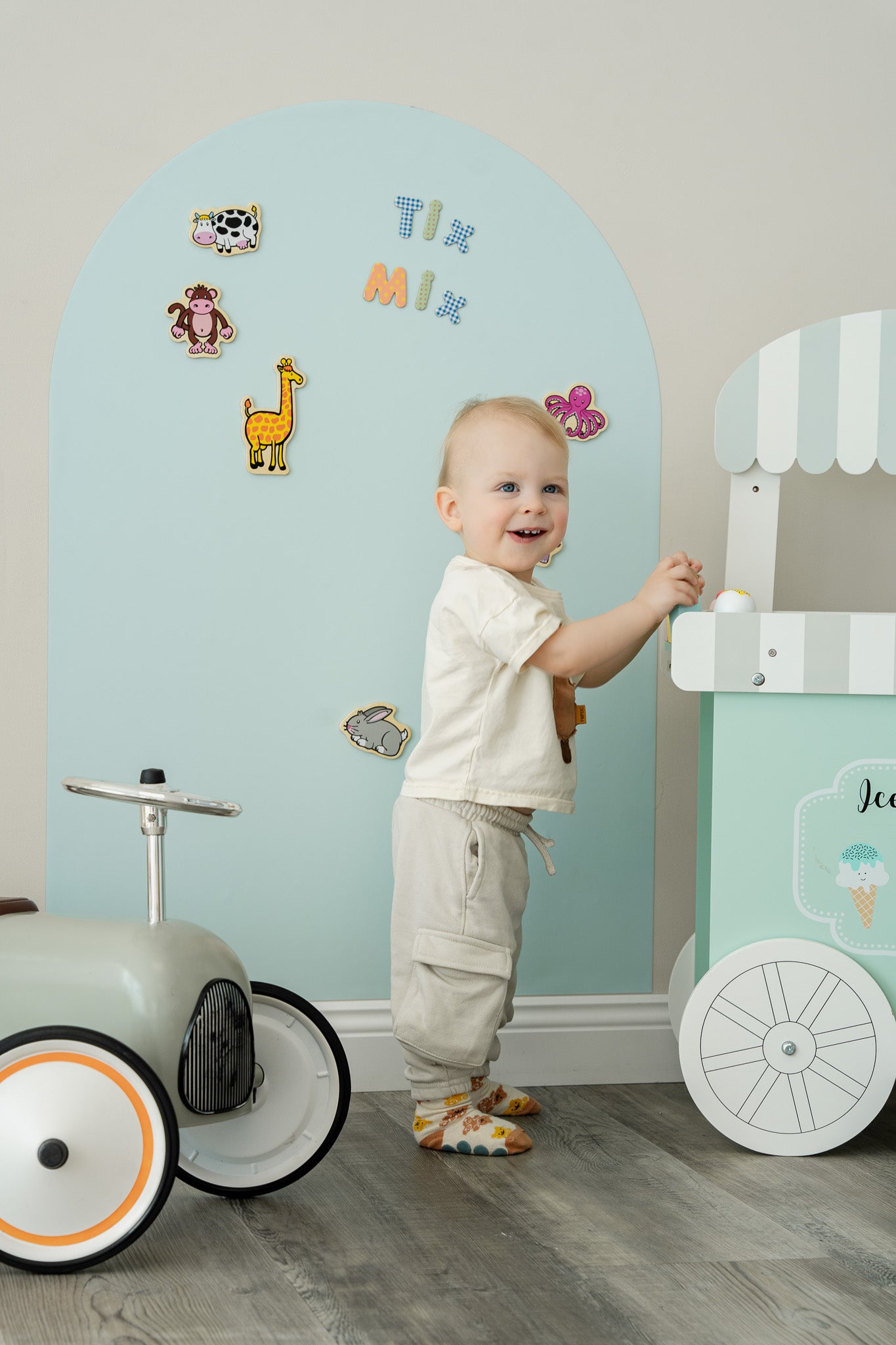 A toddler standing happily in front of Tix&Mix magnetic wall decal in blue dream color.