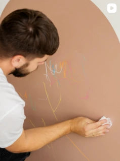 Man applying decorative elements to a wall with a brown background