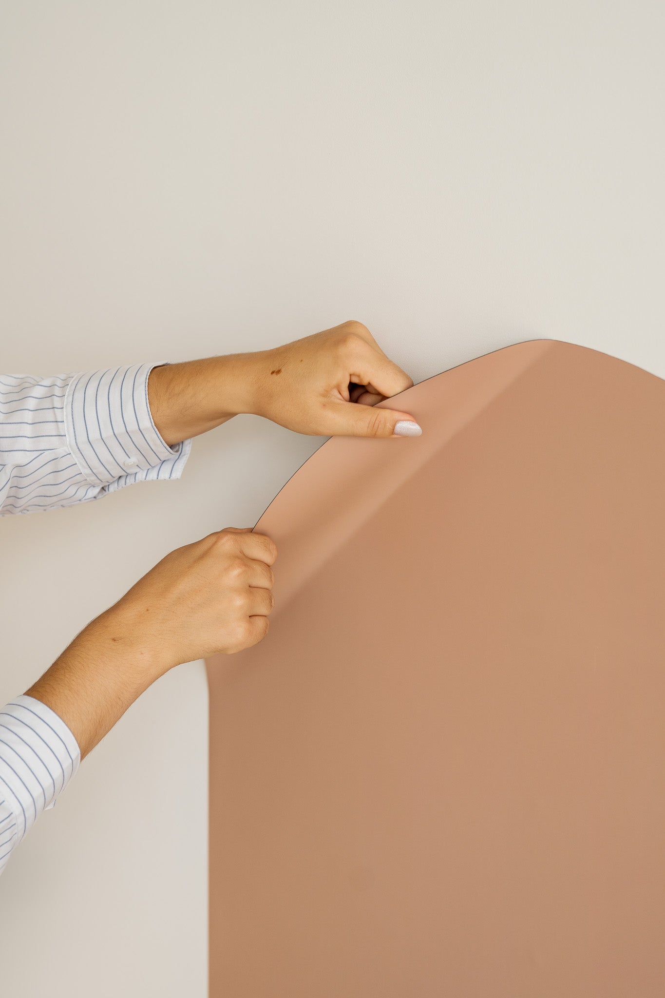 A parent mounting the Tix&Mix magnetic wall decal on a clean white wall.