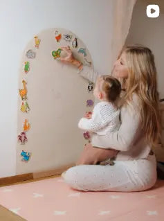 Woman holding a baby in a room with colorful wall stickers.