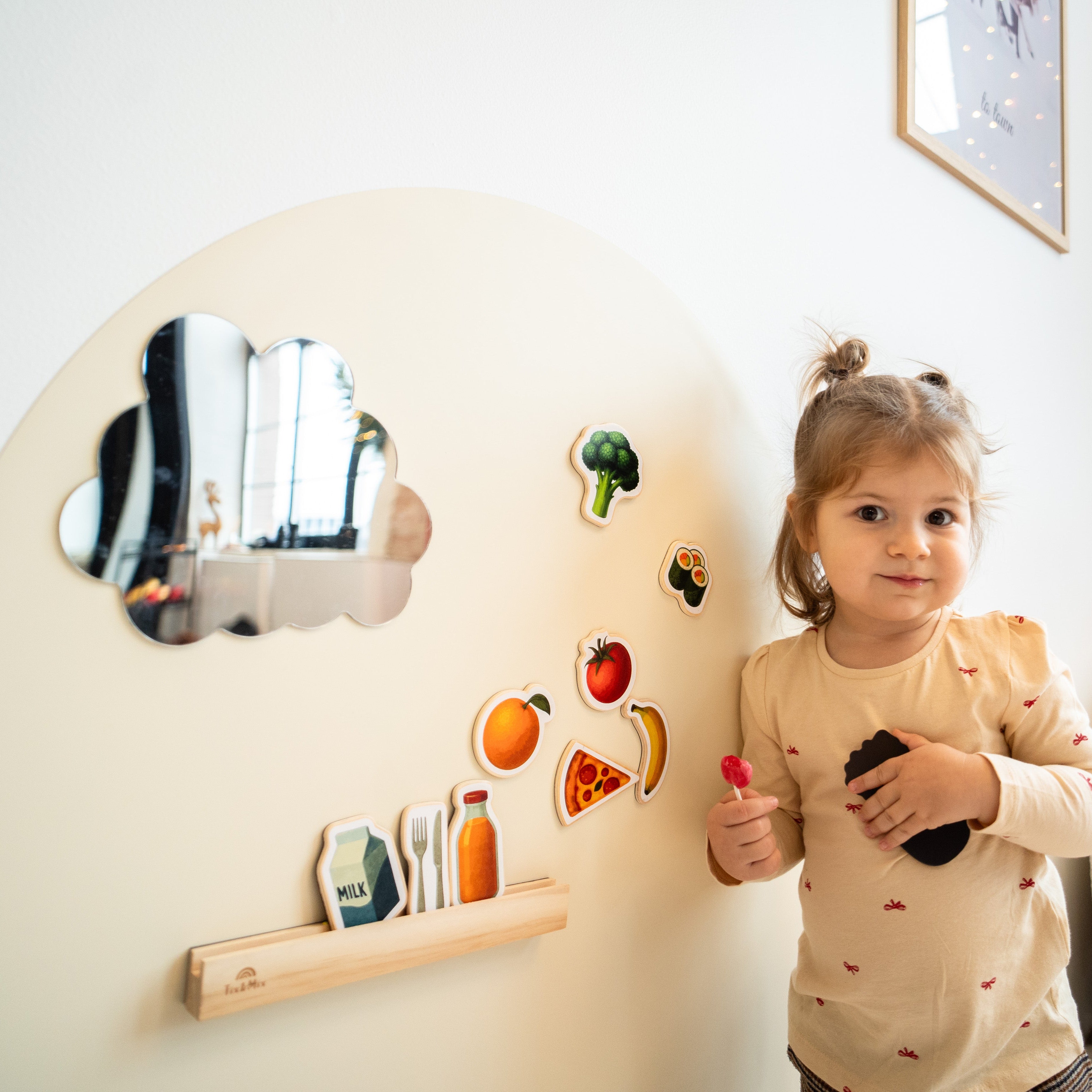 A toddler playing with Tix&Mix magnetic wall decal with food-themed magnetic toys.