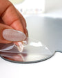 A hand removing the white outer sticker from the Tix&Mix magnetic mirror.