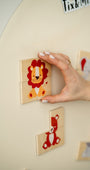 A hand arranging a tiger puzzle on a magnetic wall decal.