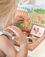 A child playing with Tix & Mix magnetic animal puzzle set, placing farm-themed magnets on a reusable board inside a wooden storage box.