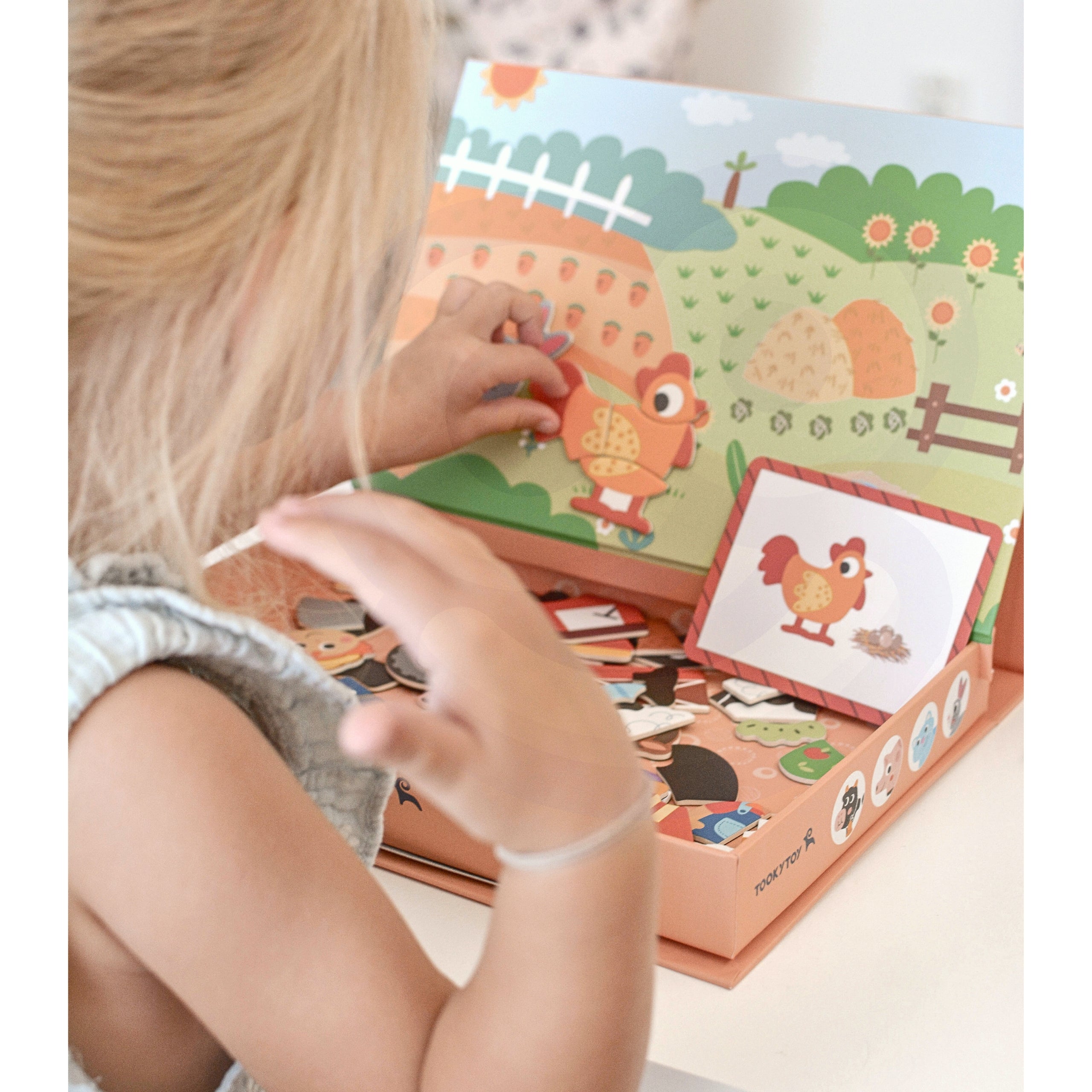 A child playing with Tix & Mix magnetic animal puzzle set, placing farm-themed magnets on a reusable board inside a wooden storage box.