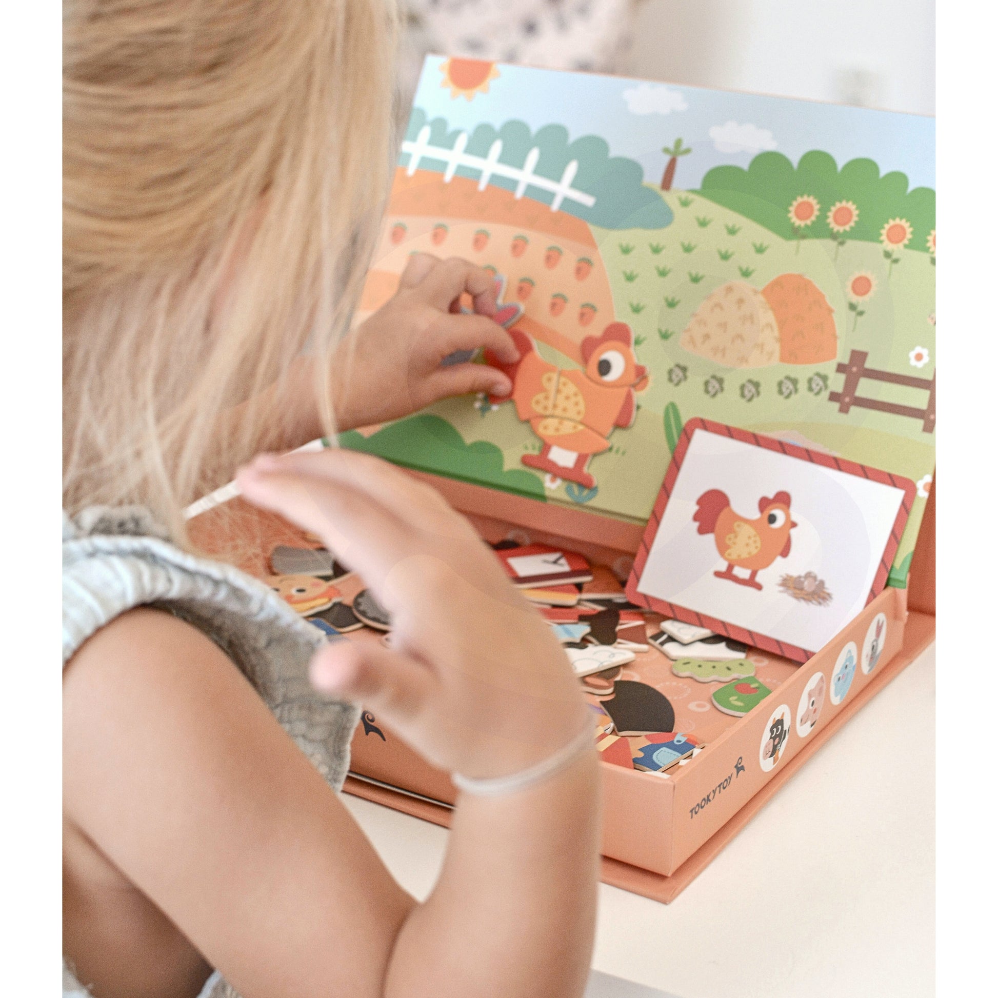 A child playing with Tix & Mix magnetic animal puzzle set, placing farm-themed magnets on a reusable board inside a wooden storage box.
