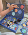 A toddler playing with Tix & Mix Space Exploration set on a wooden storage box.