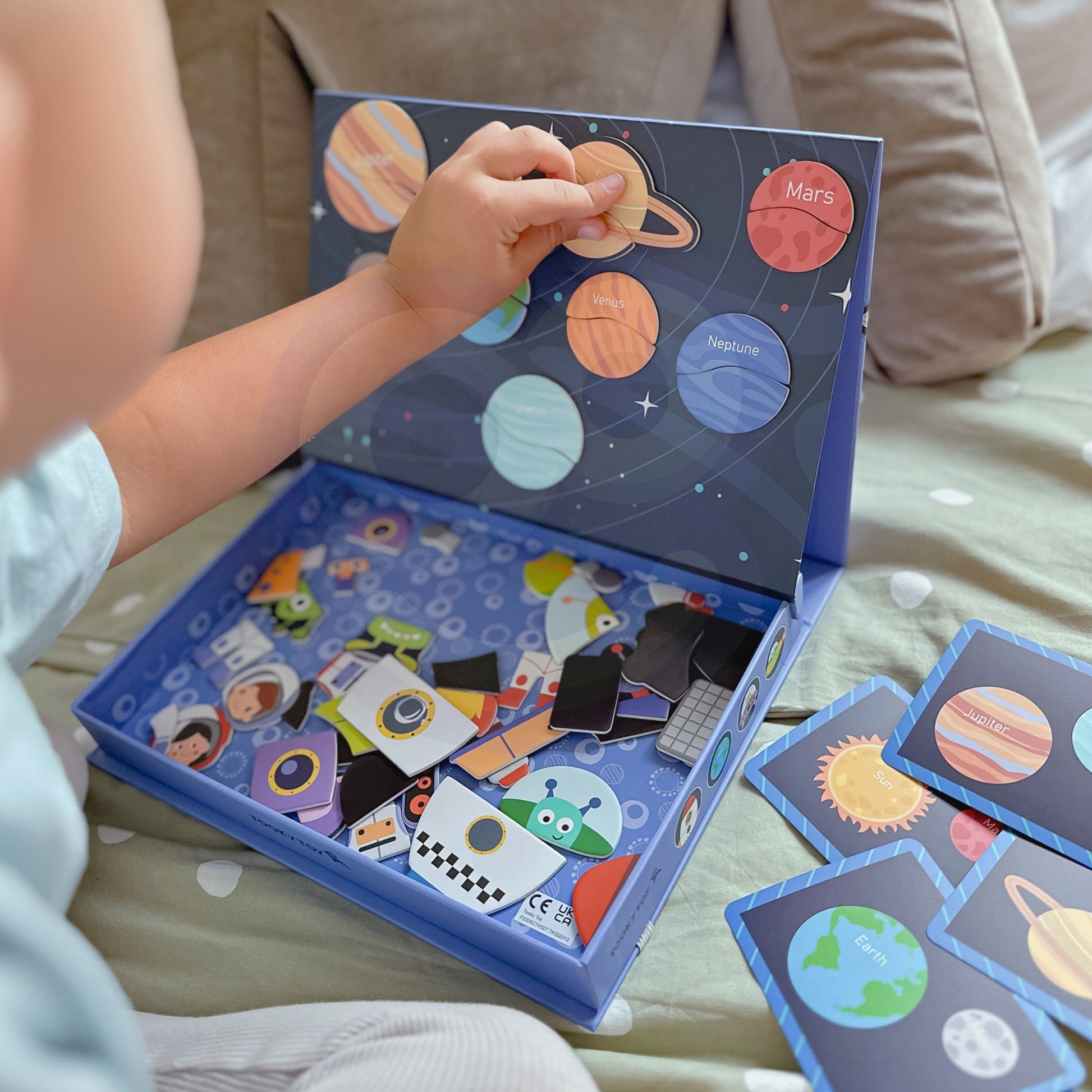A toddler playing with Tix & Mix Space Exploration set on a wooden storage box.