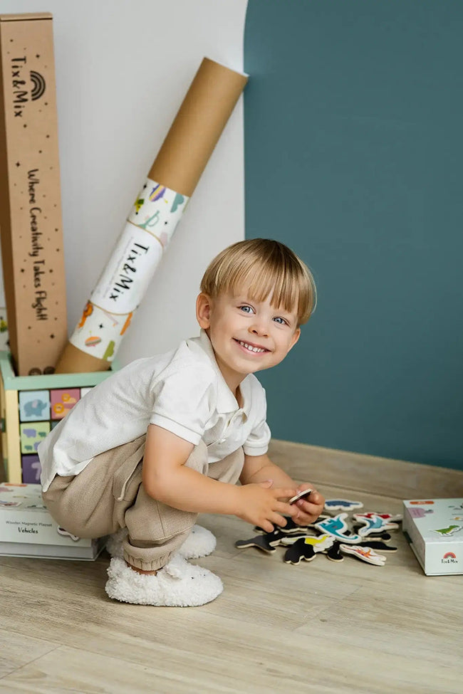 A toddler happily playing with Tix&Mix wooden magnetic toys while looking at the camera.