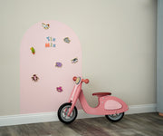 A product display of Tix&Mix pink magnetic wall decal with magnetic animals toys on it and a kiddie bicycle on the side.