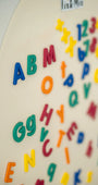 A close up photo featuring the Tix&Mix magnetic alphabet letters on a white wall decal.