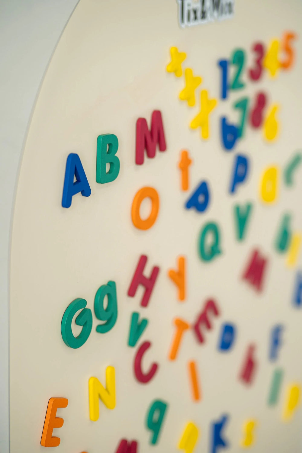 A close up photo featuring the Tix&Mix magnetic alphabet letters on a white wall decal.