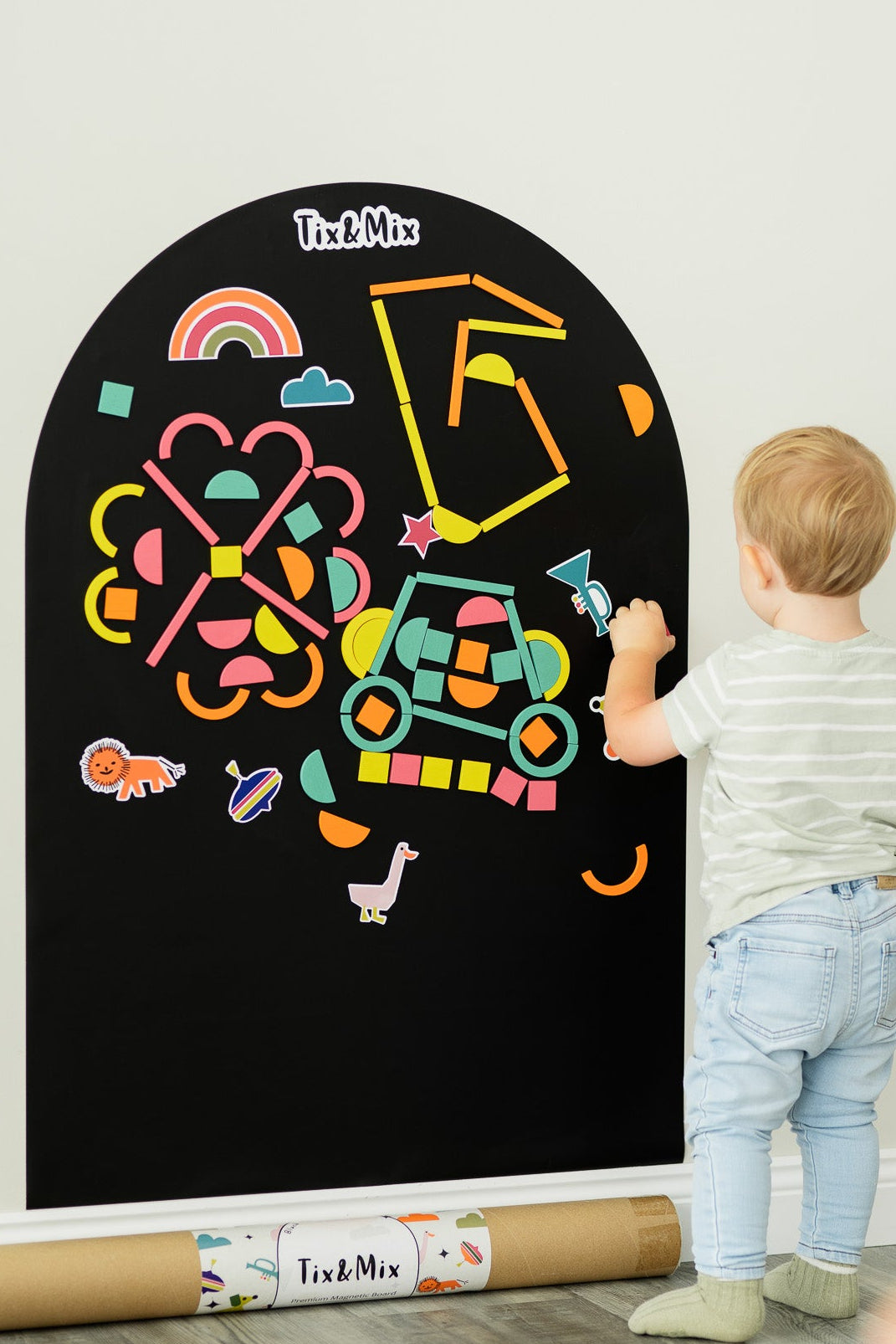 Child drawing on a magnetic wall decal with colorful crayons in a room.