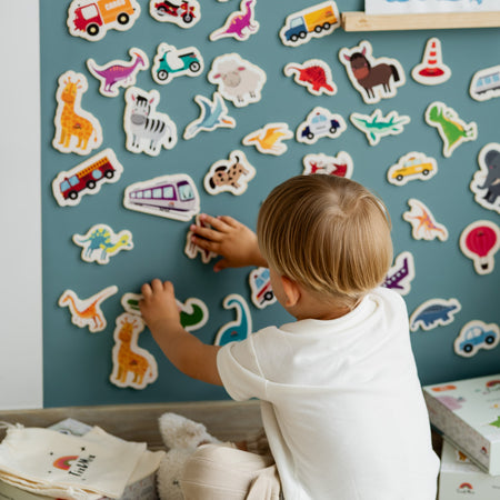 A kid playing with magnetic toys on a magnetic wall board.