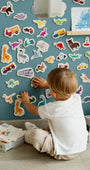 A male kid playing with Tix&Mix magnetic animals and vehicles toys on a cyan wave wall decal.