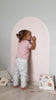 A toddler playing with Tix&Mix magnetic toys on a pink magnetic wall decal.