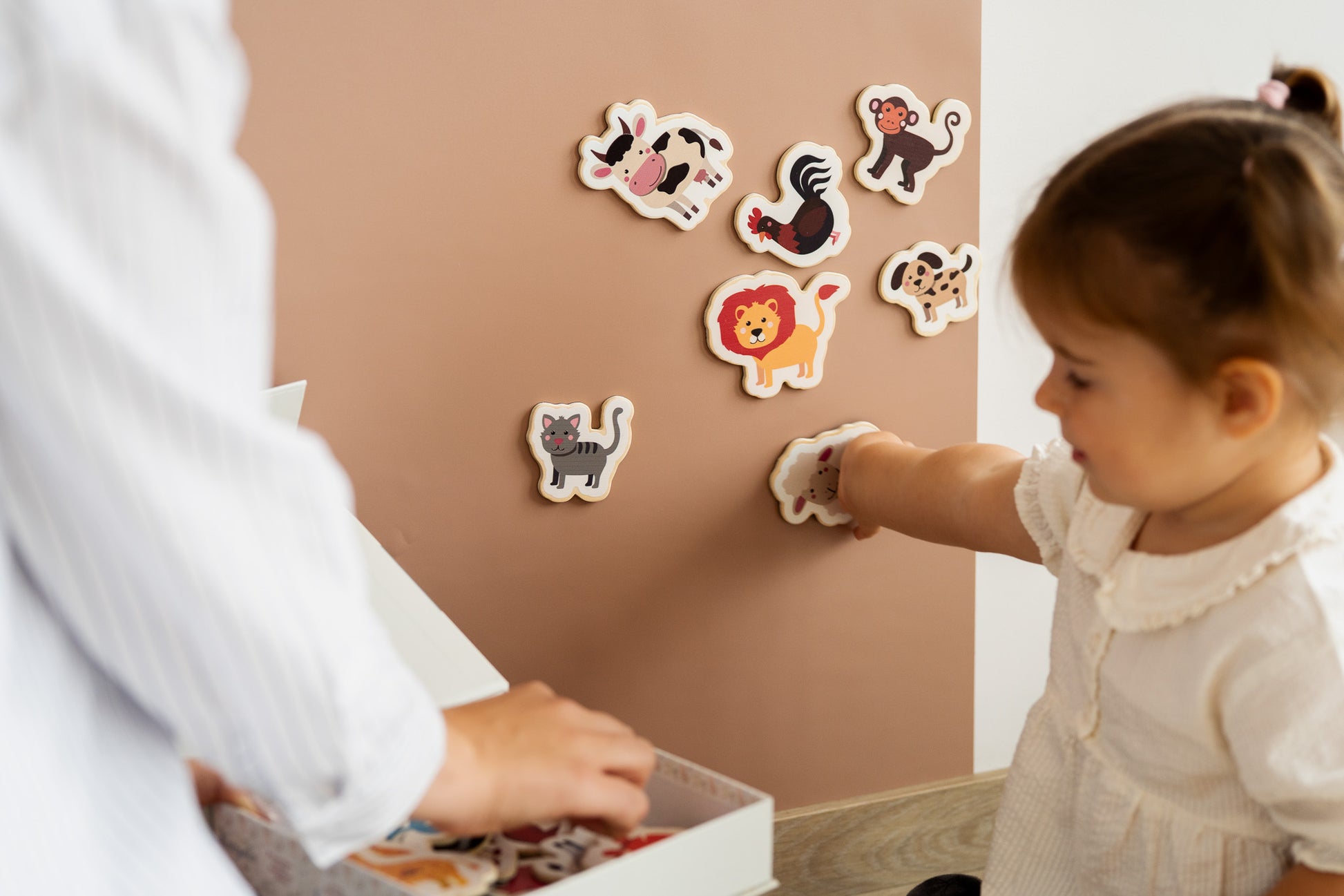A toddler playing with Tix&Mix explore the animals toy set on a brown magnetic wall decal.